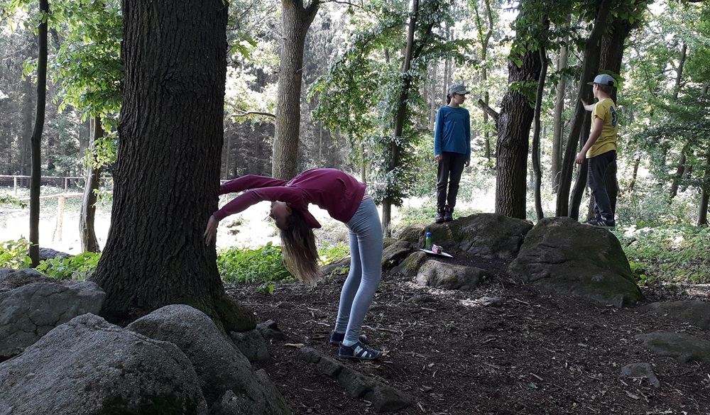 Skupina dětí s klacky a bylinkami na cestě v lese