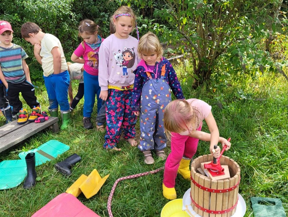 Děti lisují jablečný mošt na ručním lisu
